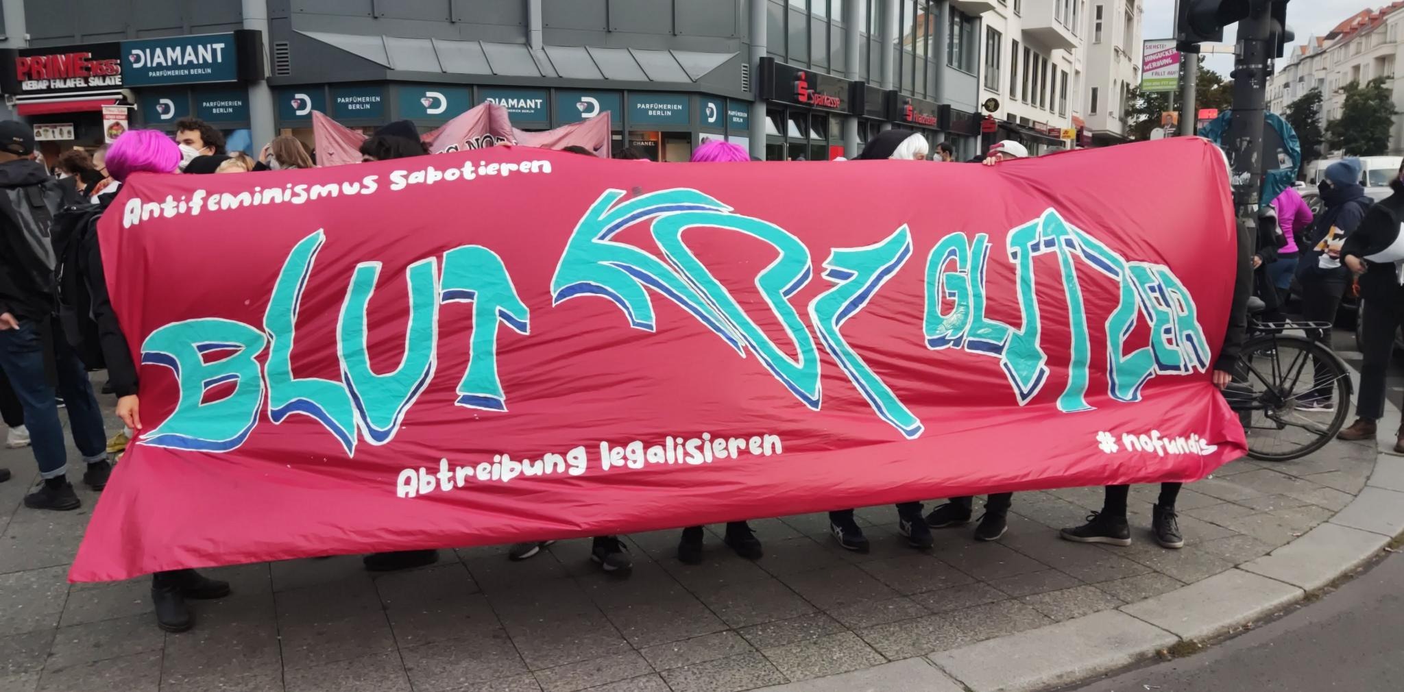 Foto des Fronttranspis der Demo. Auf dem Transp steht: Blut Kot Glitzer